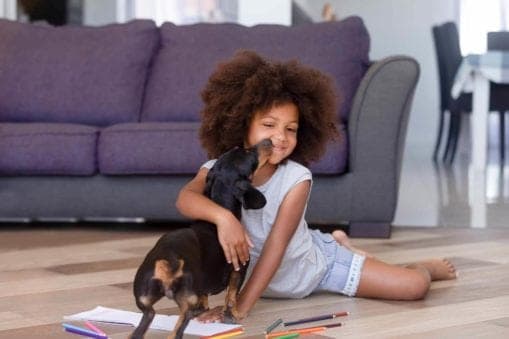 Girl sitting on floor hugging dog