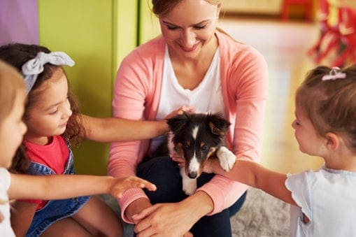 Woman holding dog while small children pet it